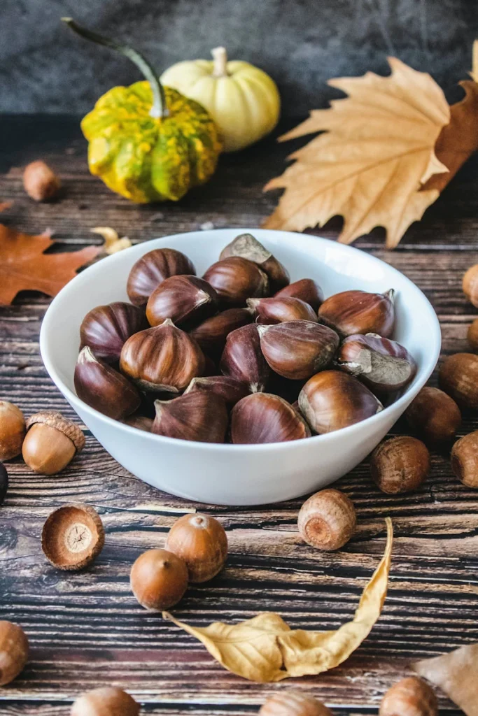 bowl of chestnuts with autumn decorations and acorns around