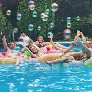 adult friends playing in pool with bubbles creating happy memories together